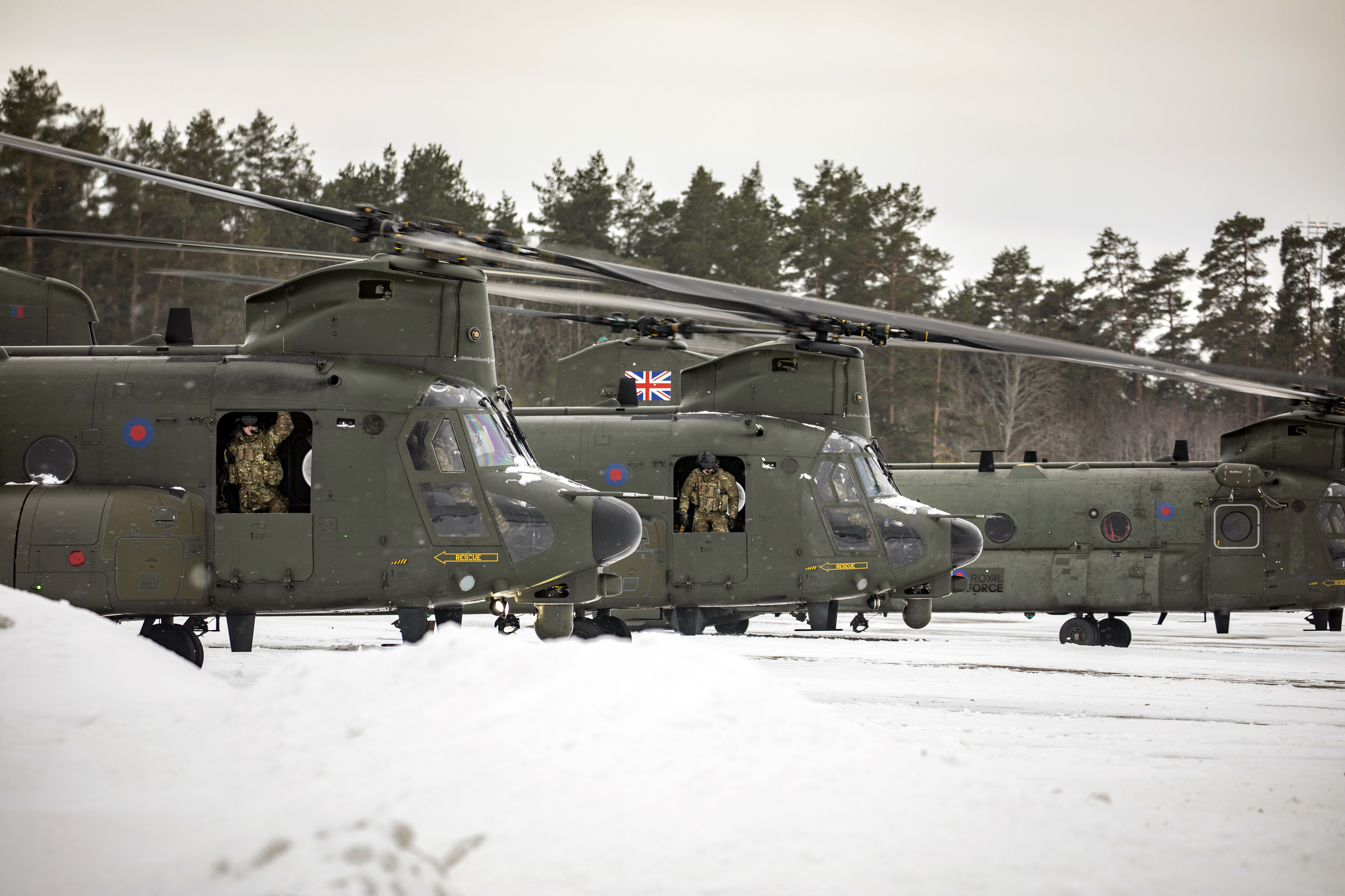 Image shows RAF Chinooks in a row, on a snowy airfield.